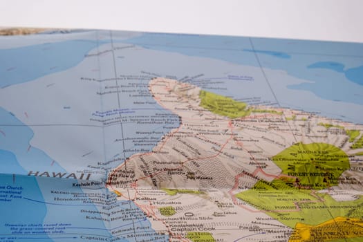Close up detail of a colorful map focusing on Hawaii through selective focus, background blur with a white horizon line in background