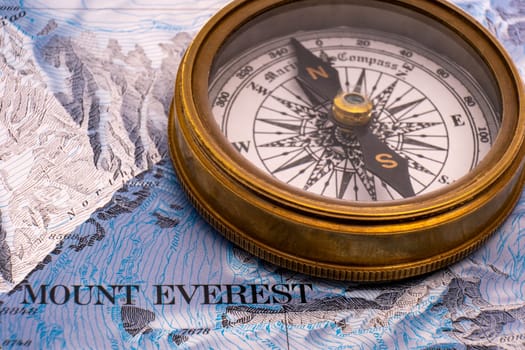 Close up of vintage brass compass on map detail of Mt. Everest topographical map showing contour lines, elevation. High quality photo