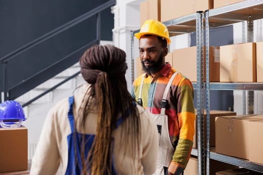 African american postal warehouse trainee listening to manager instruction. Delivery service storehouse new worker discussing parcels storing system in shipment company storage room