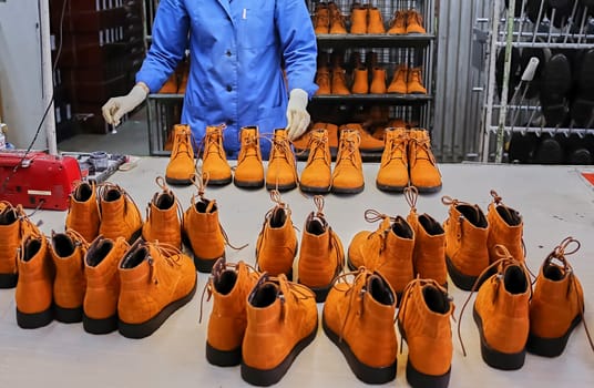 Checking the quality of shoes in a shoe factory. Yellow boots, finished shoes.