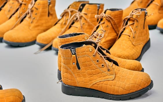 Checking the quality of shoes in a shoe factory. Yellow boots, finished shoes.