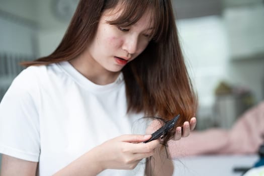 Asian woman have problem with long hair loss attach to comb brush.