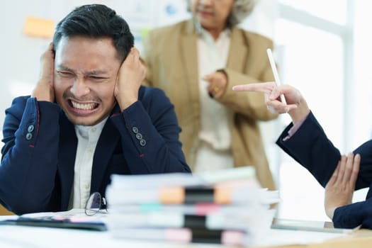 An image of an Asian male employee looking worried and sad about being scolded by his boss for failing to meet sales targets, concept of disappointment and failure in his career.