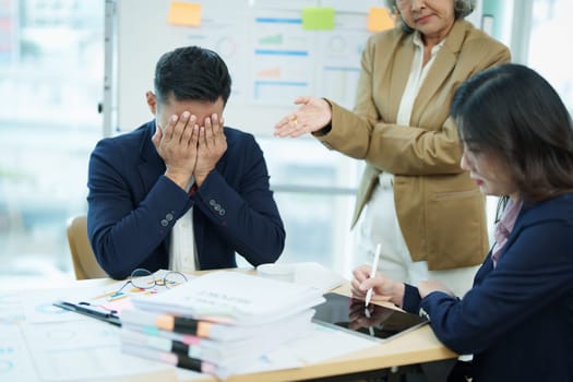 An image of an Asian male employee looking worried and sad about being scolded by his boss for failing to meet sales targets, concept of disappointment and failure in his career.