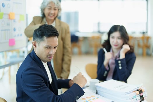 An image of an Asian male employee looking worried and sad about being scolded by his boss for failing to meet sales targets, concept of disappointment and failure in his career.