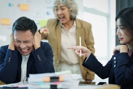 An image of an Asian male employee looking worried and sad about being scolded by his boss for failing to meet sales targets, concept of disappointment and failure in his career.