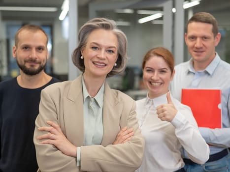 Portrait of four office workers. A gray-haired mature woman, a Caucasian man, a bearded man and a red-haired woman