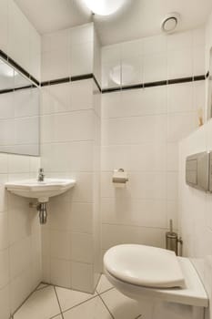 a small bathroom with white tiles and black trim on the walls, there is a mirror above the toilet bowl