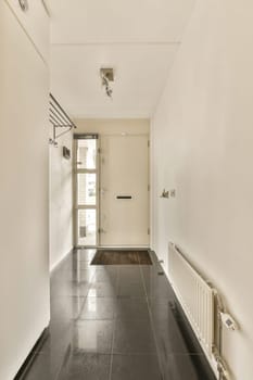 a long hallway with black tiles on the floor and white walls in an empty room that appears to be used