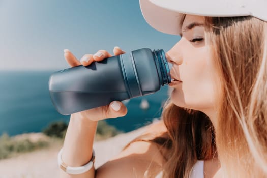 Fintess woman drinking water. Happy, active middle aged woman standing on beach and drinking water after excersise. Concept of lifestyle, sport. Close up.