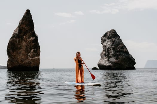 Close up shot of beautiful young caucasian woman with black hair and freckles looking at camera and smiling. Cute woman portrait in a pink bikini posing on a volcanic rock high above the sea