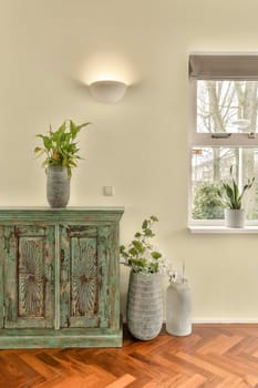 some plants in vases on a wooden floor next to an old dresser and sideboard with two pots