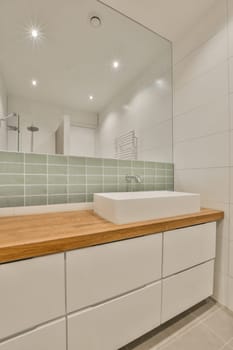 a modern bathroom with white cabinets and green tiles on the wall behind it is a large mirror above the sink