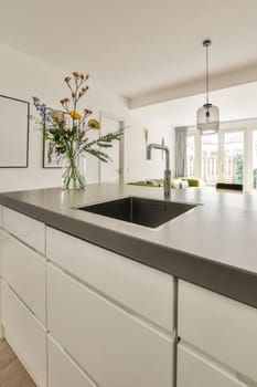 a modern kitchen with white cabinets and black counter tops in the center of the image is a vase of flowers