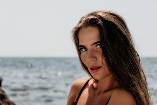 Woman travel sea. Young Happy woman in a long red dress posing on a beach near the sea on background of volcanic rocks, like in Iceland, sharing travel adventure journey