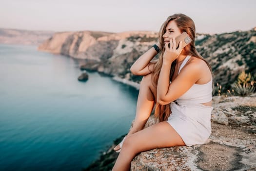 Woman travel sea. Young Happy woman in a long red dress posing on a beach near the sea on background of volcanic rocks, like in Iceland, sharing travel adventure journey