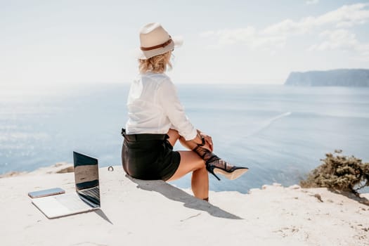 Happy girl doing yoga with laptop working at the beach. beautiful and calm business woman sitting with a laptop in a summer cafe in the lotus position meditating and relaxing. freelance girl remote work beach paradise