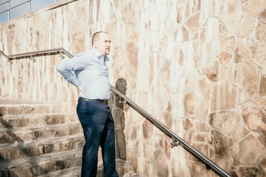 Portrait of a senior professional man in a suit with various problems. A middle-aged businessman with a briefcase descends the stairs.