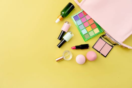 Bright summer eyeshadow palette and makeup products in pink cosmetic bag on green background. Makeup cosmetics. Colorful colors. Place for text. Flat lay. Top view. layout