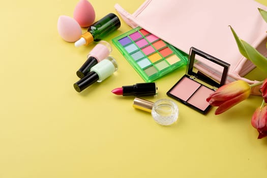 Bright summer eyeshadow palette and makeup products in pink cosmetic bag on green background. Makeup cosmetics. Colorful colors. Place for text. Flat lay. Top view. layout