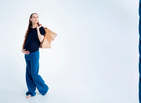 Shopping concept: Young pregnant woman with shopping bags full length portrait on white background.