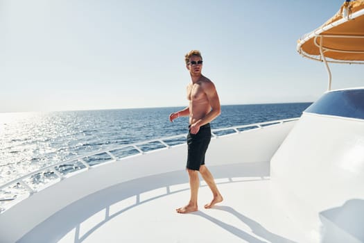 In sunglasses. Young male tourist is on the yacht on the sea. Conception of vacation.