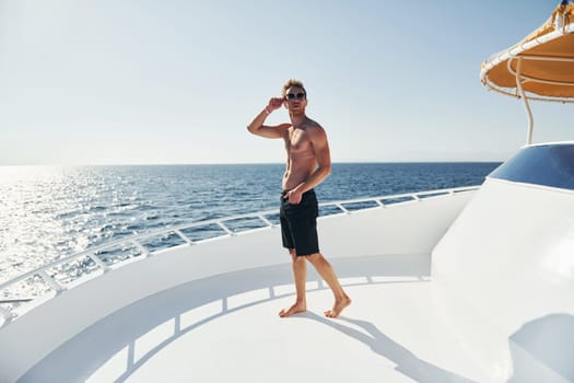 In sunglasses. Young male tourist is on the yacht on the sea. Conception of vacation.