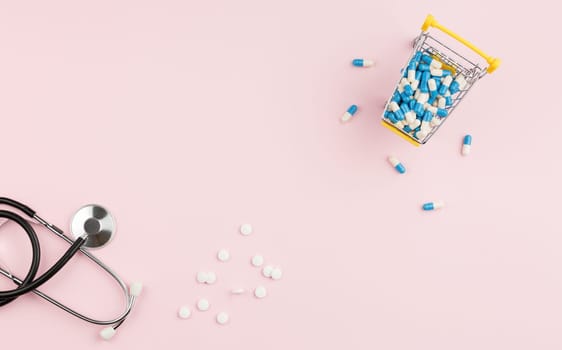 Supermarket trolley filled with pills on a pink background. Top view. Pharmacy concept. Stethoscope on the doctor table.