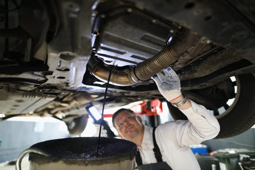 Auto mechanic repairman inspecting car engine in garage of service station. Car repair concept