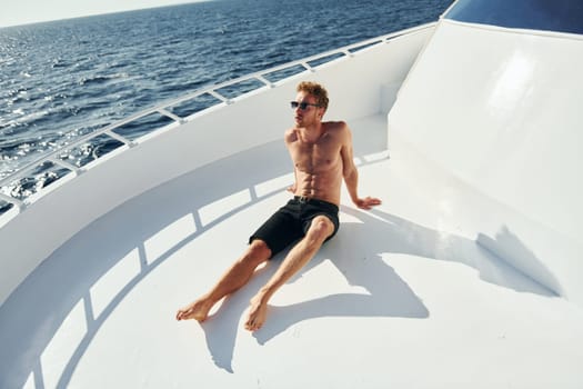 In sunglasses. Young male tourist is on the yacht on the sea. Conception of vacation.