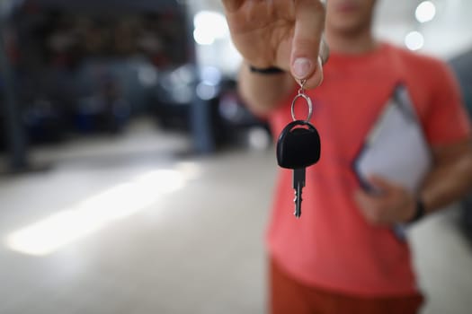 Person mechanic handing over key to car in workshop. Guarantee of quality auto repair concept