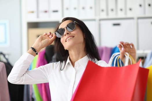 Smiling woman in sunglasses with shopping bags. Shopping and positive mood