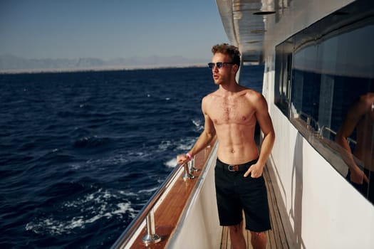 Warm weather. Young male tourist is on the yacht on the sea. Conception of vacation.