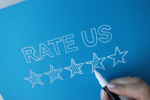 Person paints star next to message rate us. Rating and evaluation of customers concept