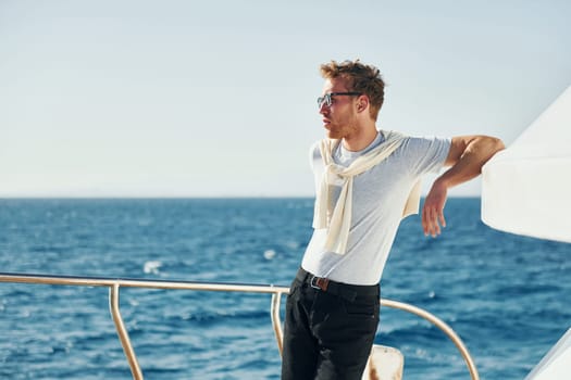 Warm weather. Young male tourist is on the yacht on the sea. Conception of vacation.