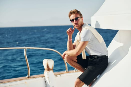 Posing for a camera. Young male tourist is on the yacht on the sea. Conception of vacation.