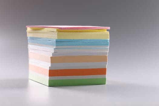 Stack of multicolored sticky notes on gray background. Stack of blank multicolor square note paper concept