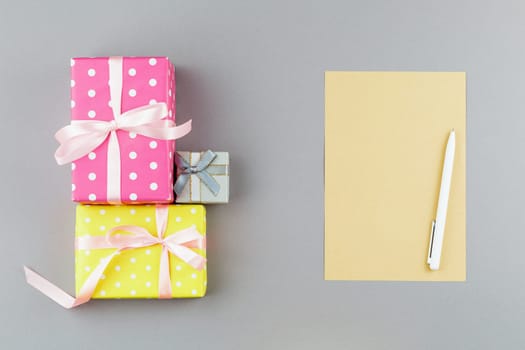 Presents in wrapping paper with polka dots on gray isolated background. Top view. Craft note sheet with white pen. Flat lay.