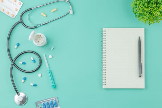 Medical equipment with stethoscope and spiral notebook in doctor office on green desk background top view. Nurse desktop concept.