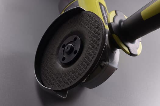 Powerful angle grinder with abrasive disc on gray background. Construction tool concept