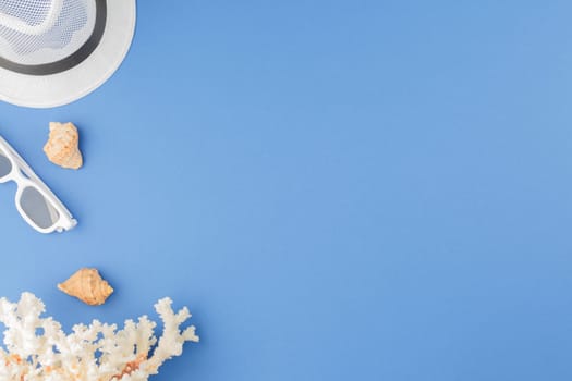 Seashells with corals on a blue isolated background. Top view. Summer vacation concept. Beach hat with sunglasses. Flat lay.