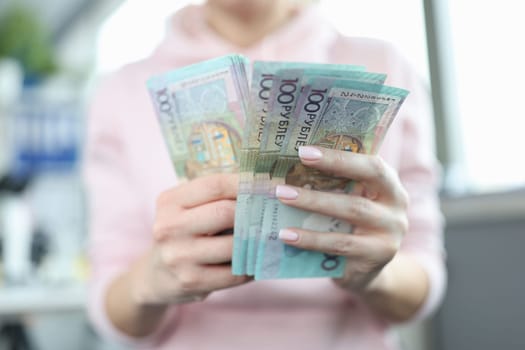 Women hands hold one hundred ruble Belarusian banknotes. Ruble inflation and rising prices in Belarus concept