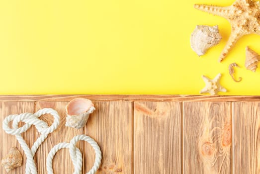 Nautical rope and seashells on wooden background with yellow copy space. Flat lay. Summer vacation concept. Starfish and seahorse. Top view.