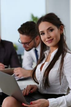 Smiling businesswoman with laptop and team of partners in office. Teamwork in business concept