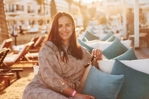 Sitting on the chair. Happy mature woman is outdoors enjoying her vacation at sunny daytime.