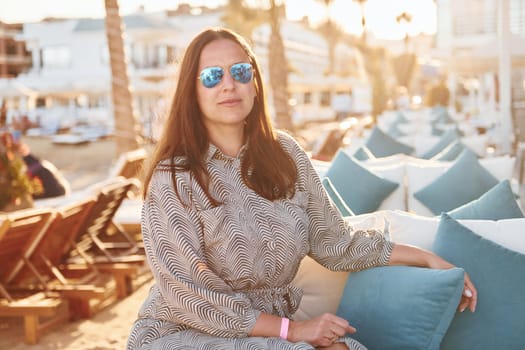 Sitting on the chair. Happy mature woman is outdoors enjoying her vacation at sunny daytime.