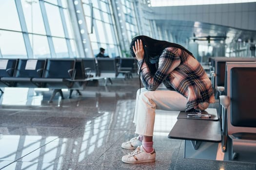 Sad young girl crying when sitting in the modern airport.