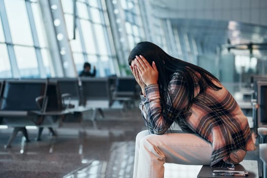 Sad young girl crying when sitting in the modern airport.
