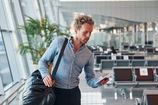 Young man in formal wear is in modern airport. Conception of vacation.