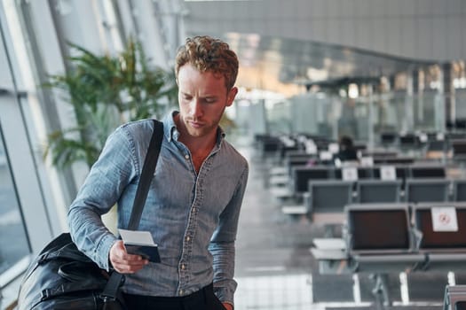 Young man in formal wear is in modern airport. Conception of vacation.